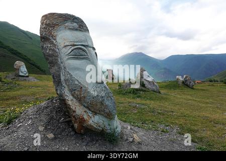 Paysage de montagne avec cercle de pierre dans la région du Haut Khevsureti avec des champs herbeux et des sommets lointains Banque D'Images