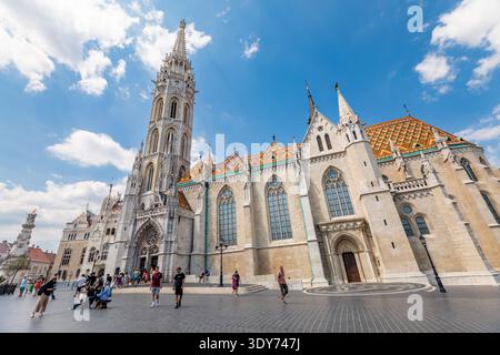 Les visiteurs profitent d'une journée ensoleillée près de la tour de l'église Matthias et de la façade dans le quartier du château de Budapest tout en explorant les environs et en prenant des photos Banque D'Images