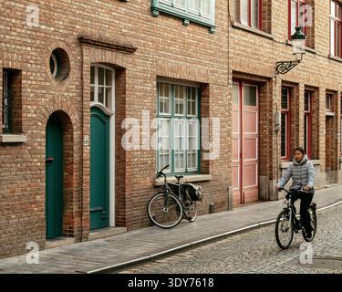 Promenez-vous à pied à vélo devant des bâtiments résidentiels à Bruges, en Flandre alors que le crépuscule s'installe Banque D'Images