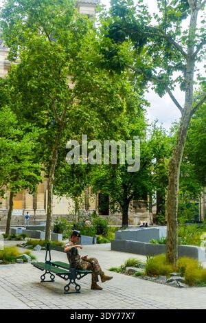 Soldat assis dans le jardin en souvenir des événements du 13 novembre devant l'église pendant l'été à Paris, France Banque D'Images
