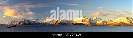 Les montagnes enneigées s'élèvent au-dessus de la mer sous un ciel dégagé sur l'île de Vestvagoy dans les îles Lofoten, en Norvège Banque D'Images
