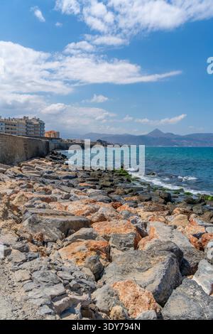 Vue de jour ensoleillée de la côte rocheuse avec l'eau bleue et les bâtiments à Héraklion, Crète, Grèce Banque D'Images