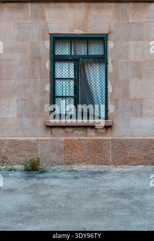 Façade d'une vieille maison, fenêtre en fer avec des rideaux blancs battant au vent. Banque D'Images