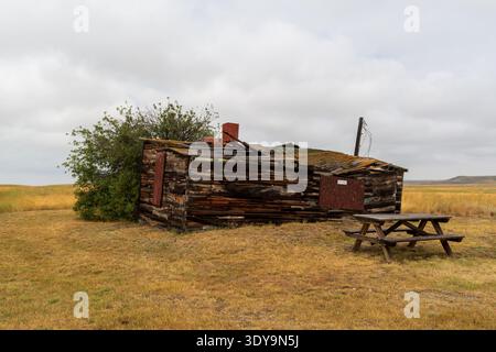 Val Marie, SK Canada - 05 août 2024 : une cabane altérée avec une cheminée en pierre se dresse sur le site Larson Ranch dans le parc national des Prairies. Banque D'Images