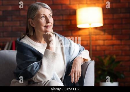 Femme aînée réfléchie sur fauteuil à la maison Banque D'Images