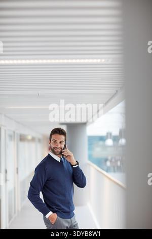 Heureux, homme d'affaires et parler avec appel téléphonique sur le balcon pour la communication ou la discussion. Homme, employé ou agent avec sourire sur smartphone mobile pour Banque D'Images