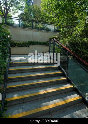 Une vue verticale d'un escalier en pierre entouré d'arbres verts et de feuillage dans un jardin résidentiel calme et moderne. Banque D'Images