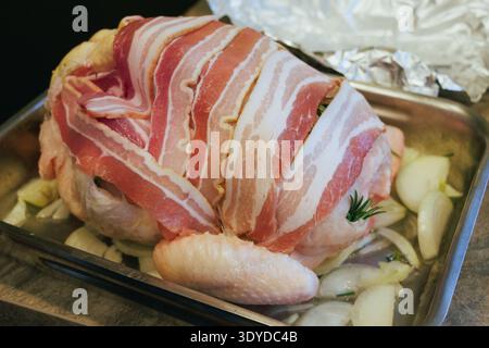Bacon cru recouvrant la dinde entière en préparation de la cuisson dans une rôtissoire Banque D'Images