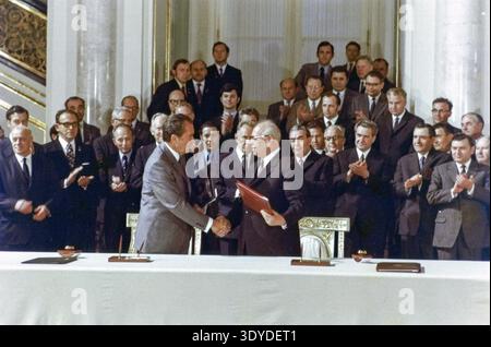 Dans cette importante photographie de 1972, le président Richard Nixon serre la main du président Nikolaï Podgorny au sommet de Moscou, marquant un moment de progrès diplomatique entre les États-Unis et l'Union soviétique pendant la guerre froide. Une importante délégation d'hommes en costume se tient derrière eux, beaucoup applaudissant cet accord historique. L'événement symbolise l'ère de détente et les efforts pour réduire les tensions entre les superpuissances mondiales. Banque D'Images