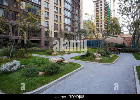Un chemin de gravier divergent et pavé serpentant à travers un jardin verdoyant magnifiquement aménagé dans une communauté sereine. L'image véhicule une vie harmonieuse Banque D'Images