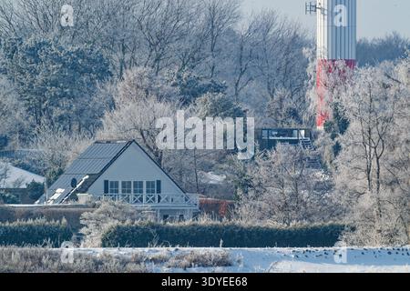 Une scène hivernale sereine avec une maison blanche entourée d'arbres givrés et d'un sol couvert de neige, capturant la beauté calme d'une journée de saison froide. Banque D'Images