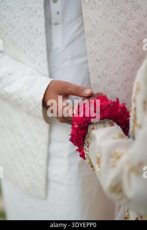 Gros plan d'un marié sud-asiatique tenant la main de la mariée lors d'une cérémonie de mariage traditionnelle, avec un motif complexe de henné (mehndi) Banque D'Images