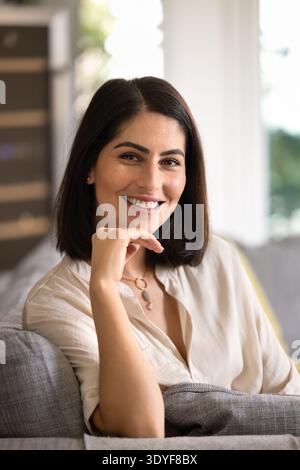 Heureuse femme hispanique dans la pose décontractée à la maison confortable Banque D'Images