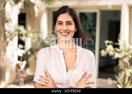 Heureux confiant jeune femme latino propriétaire debout dehors Banque D'Images