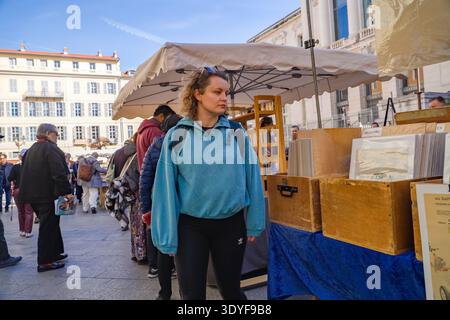 Marché à la Brocante et aux livres à la place du Palais de Justice. Femme parcourant des objets de collection devant le palais de justice historique Nice, France. Banque D'Images
