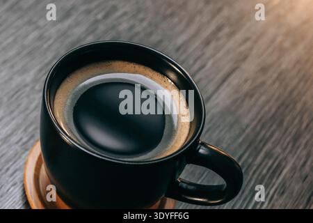 Tasse noire de café rempli de café sombre et intense sur une table grise - scène de petit déjeuner confortable Banque D'Images