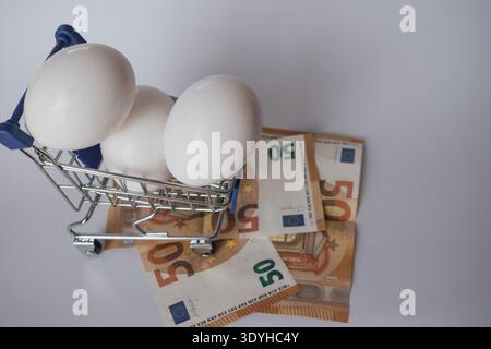 Oeufs dans un panier avec des billets en euros, symbolisant l'inflation et le coût des denrées alimentaires Banque D'Images
