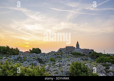 Petit village de pêcheurs (Lubenice) construit sur les rochers au-dessus de la mer avec une vue sur la mer par une journée ensoleillée au coucher du soleil sur l'île de Cres, Croatie Banque D'Images