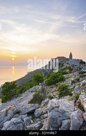 Petit village de pêcheurs (Lubenice) construit sur les rochers au-dessus de la mer avec une vue sur la mer par une journée ensoleillée au coucher du soleil sur l'île de Cres, Croatie Banque D'Images