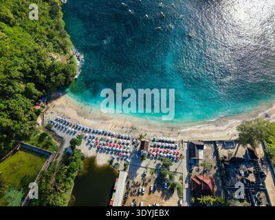 Vue en angle élevé d'une destination de plage tropicale populaire avec parasols, nageurs et mer Banque D'Images