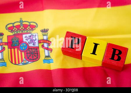Le mot PIB, Producto Interior Bruto (produit intérieur brut) écrit sur des cubes de bois jaune rouge dans le drapeau de l'Espagne. Langue espagnole. Gros plan Banque D'Images