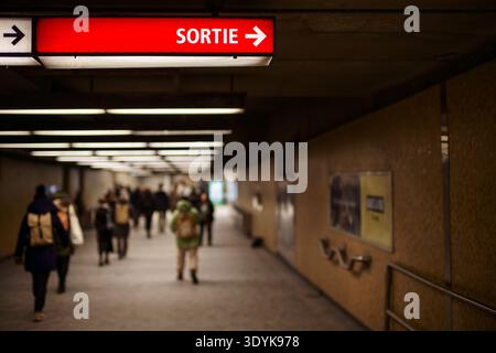 Montréal, Canada - 24 janvier 2025 : les navetteurs se déplacent dans un passage de métro sous un panneau lumineux de sortie français dans une station de métro souterraine. Banque D'Images