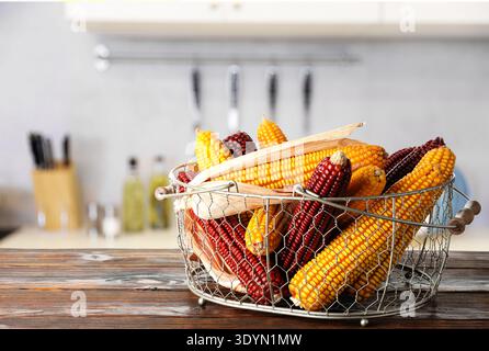 Épis de maïs rouges et jaunes dans le panier sur la table en bois dans la cuisine, espace pour le texte Banque D'Images