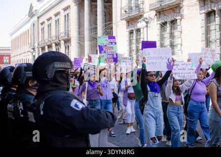 Les manifestants de 8M tiennent des pancartes et crient des slogans devant une file d'officiers de la police nationale lors de la Journée de la femme au Mexique. Banque D'Images