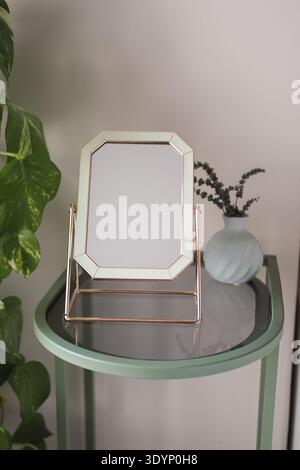 Cadre décoratif sur une table verte avec un petit vase Banque D'Images