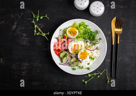 Œufs à centre mou, tomates mûres, concombre, oignon rouge, fromage cottage, et des verts mélangés avec un pansement léger. Banque D'Images