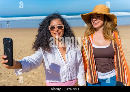Joyeuses jeunes femmes diverses prenant selfie de plage Banque D'Images