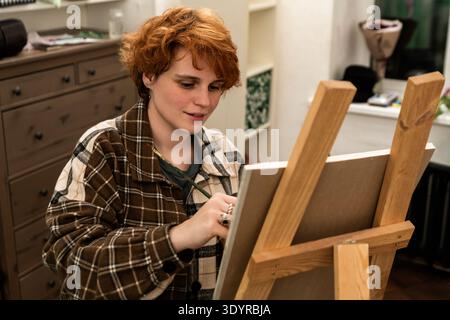 Femme peintre travaillant au pinceau sur toile en studio. Banque D'Images