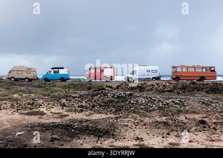 Rangée de camping-cars colorés garés le long de la route côtière accidentée de l'Atlantique près d'El Cotillo dans les îles Canaries de Fuerteventura avec un ciel spectaculaire. Banque D'Images