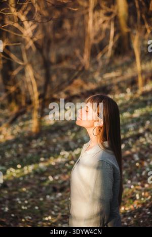 Femme au début de la forêt printanière prenant une respiration profonde Banque D'Images