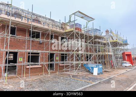Chantier de construction de logements, maisons partiellement construites recouvertes d'échafaudages, Banque D'Images