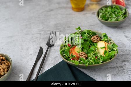 Salade fraîche mélangée avec tranches de pommes et noix servies dans un bol avec fourchette sur la table Banque D'Images