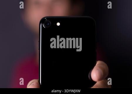 Jeune homme tenant un téléphone portable, smartphone, avec la main et le fond flou Banque D'Images