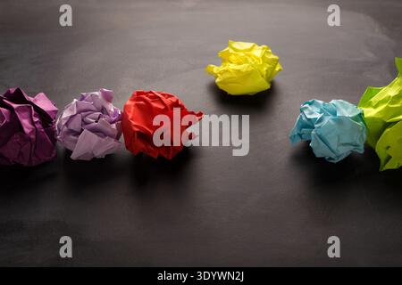 Boules de papier froissées multicolores sur fond noir Banque D'Images