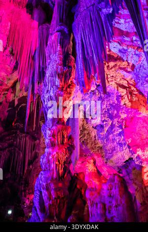 Exploration des grottes vibrantes de Gibraltar avec des formations rocheuses impressionnantes et des effets de lumière colorés lors d'une visite guidée Banque D'Images