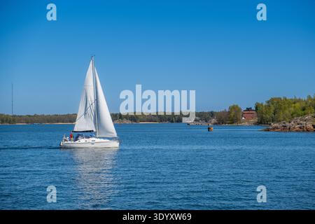 Yacht à voile sous pleine voile dans l'archipel d'Helsinki avec des îles boisées et la mer Baltique, Finlande Banque D'Images