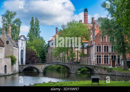 Canal de Bruges avec pont en arc de pierre et chapelle Begijnhof reflétée dans l'eau plate, Bruges, Belgique Banque D'Images