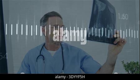 Tenant un film radiographique, médecin masculin mature portant des gommages bleus et inspectant un stéthoscope à la clinique Banque D'Images