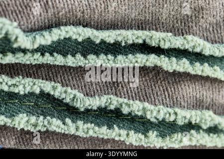 Gros plan extrême d'un tissu textile avec bords verts effilochés et surface brune nervurée Banque D'Images