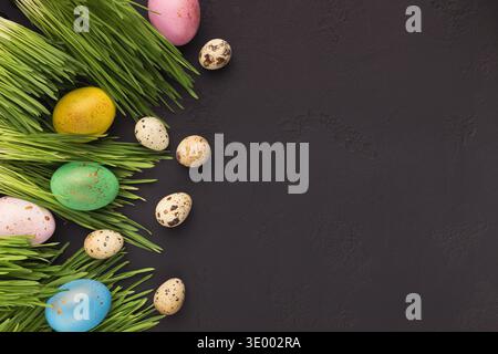 Oeufs de pâques colorés dans l'herbe verte sur fond gris Banque D'Images