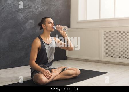 Homme de fitness buvant de l'eau au gymnase Banque D'Images
