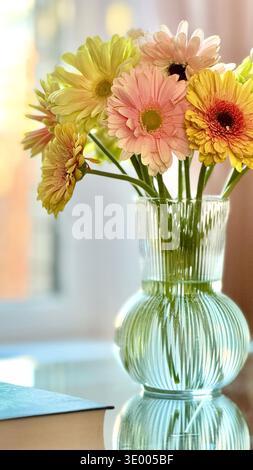 Bouquet de belles fleurs de gerbera dans un vase en verre sur une table en verre à l'intérieur Banque D'Images
