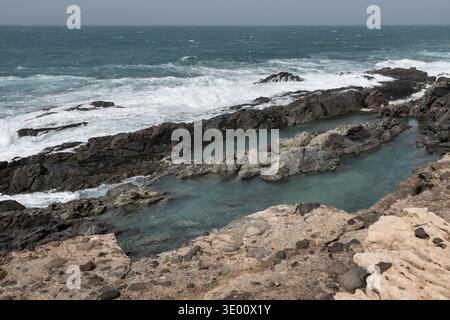 Piscines naturelles formées parmi les roches volcaniques sur la côte d'Aguas Verdes dans les îles Canaries de Fuerteventura avec des vagues de l'Atlantique et spectaculaire coasta accidentée Banque D'Images