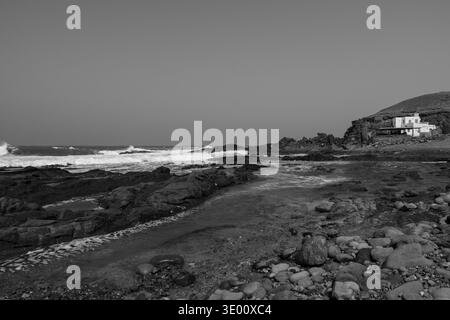 Des piscines naturelles se sont formées parmi les roches volcaniques le long de la côte d'Aguas Verdes dans les îles Canaries de Fuerteventura avec des vagues de l'Atlantique et le géolog accidenté du littoral Banque D'Images