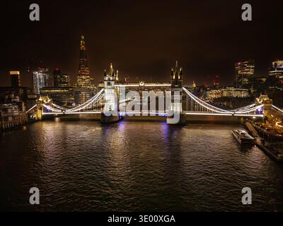 Vue aérienne du Tower Bridge illuminé enjambe majestueusement la Tamise, reflétant les lumières de la ville dans l'eau sombre, Londres, Grand Londres, United Ki Banque D'Images