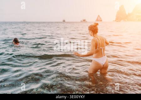 Femme, plage, mer. Jeune femme marchant dans l'eau claire de l'océan au coucher du soleil pendant les vacances d'été. Banque D'Images